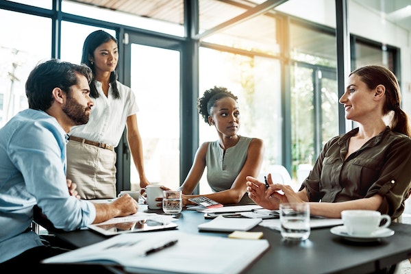 group of workers sitting and standing around a desk