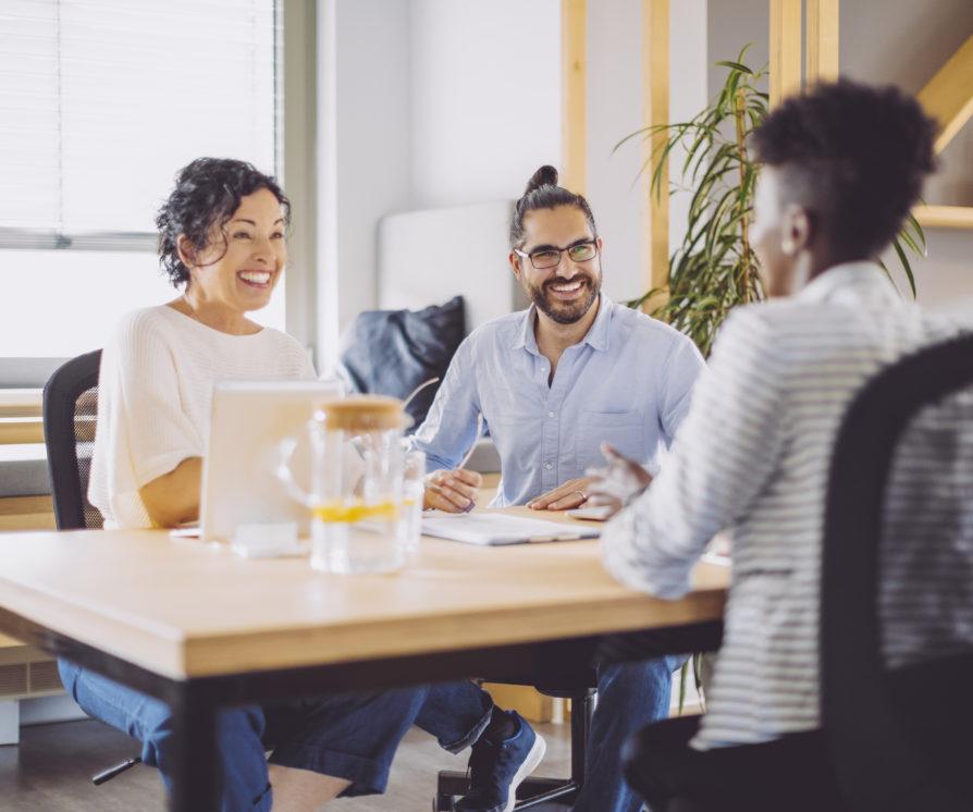 Three people sitting around a table talking