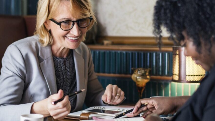 Two women meeting in a cafe with notebooks
