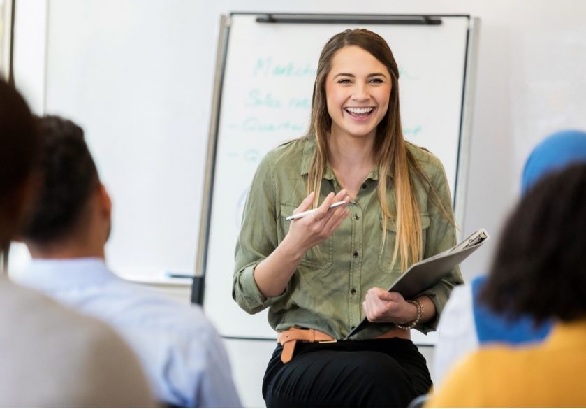 A lady smiling, giving a presentation