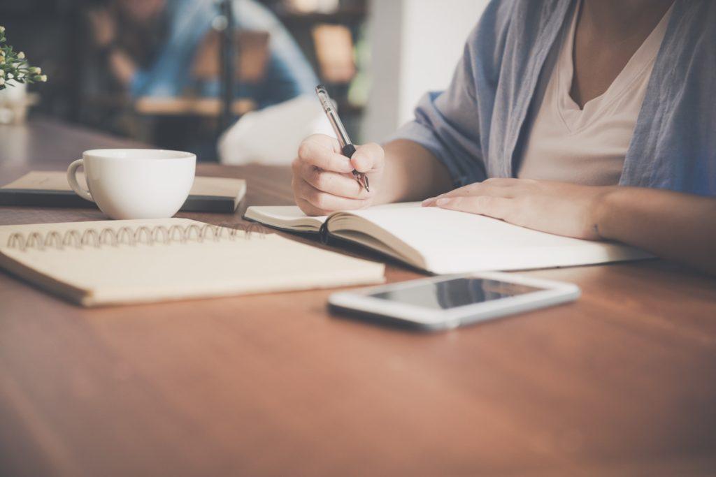woman writing on notepad at work