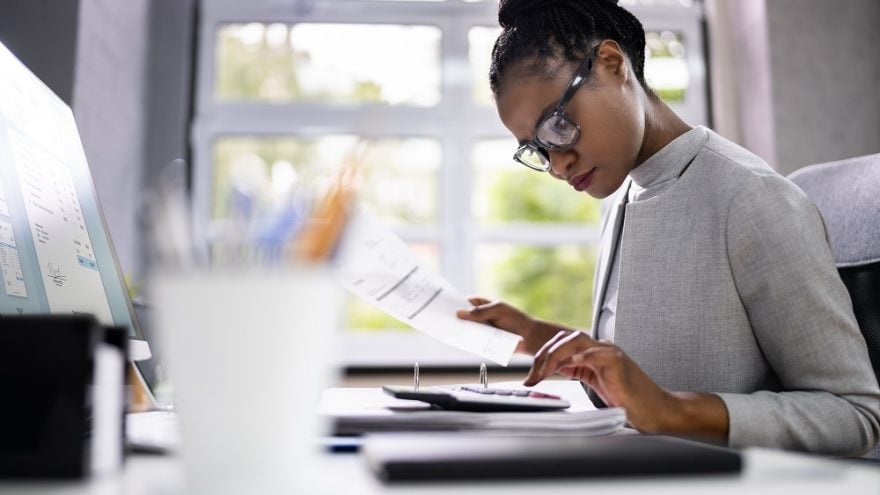 A businesswoman sat at a desk using a calculator.