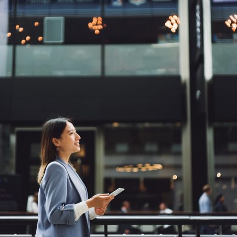 A businesswoman on a city street holding a mobile phone,