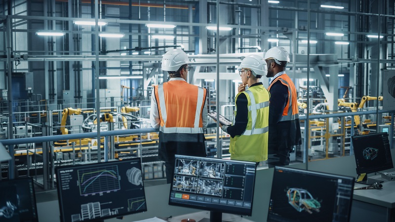 A group of engineers overseeing car manufacture in a factory.