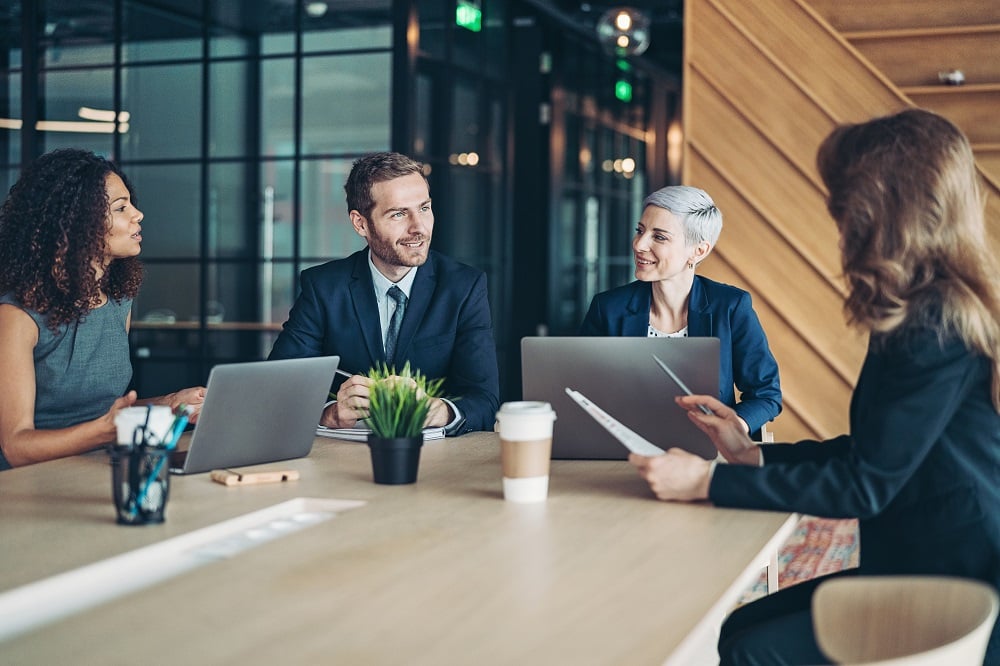 Smartly-dressed finance professionals talking in a meeting room