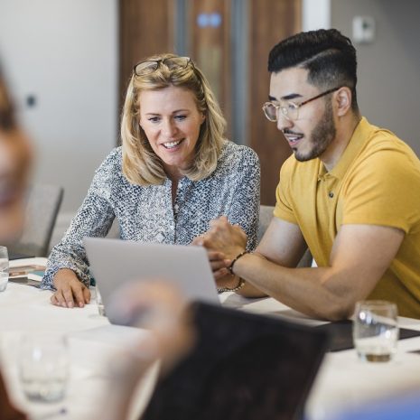 A man and woman working together on a laptop in an office.