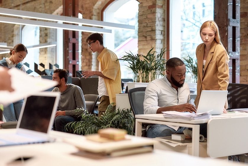 Several people working a desks in a busy open plan office.