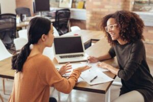 Two colleagues talking while sitting at a desk