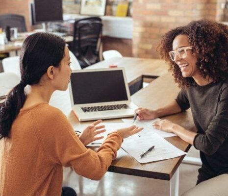 Two women talking sitting at the table.