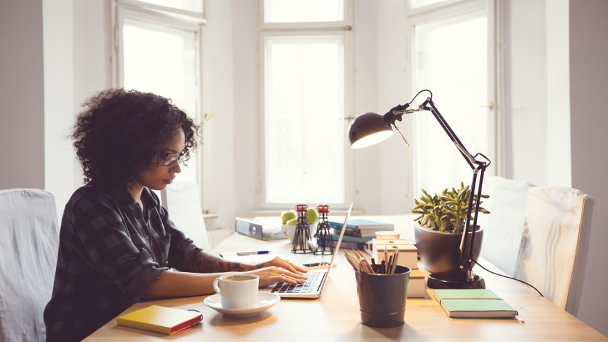 A woman working on a laptop at a home office desk.