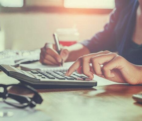 Businessman working on desk office using calculator to help her conduct her business and outsource payroll.