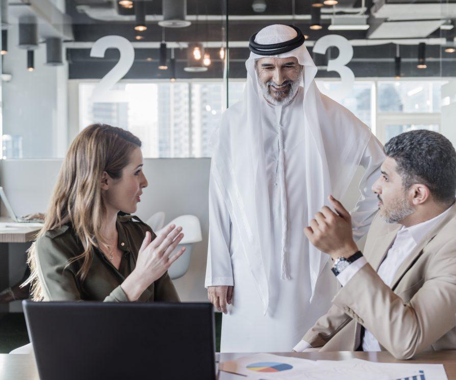 A group of three human resources professionals discussing business strategy and decisions in modern office in the Middle East.
