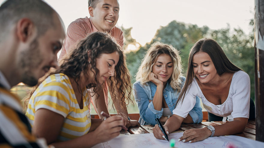 A group of people outdoors writing a plan