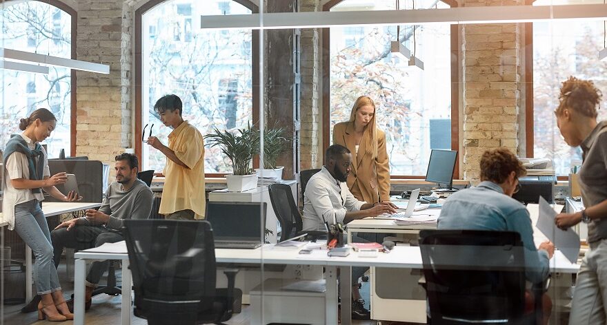 A diverse group of colleagues in brightly lit, open plan office.