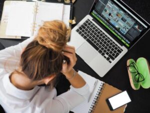 Woman with her head in her hands next to a laptop