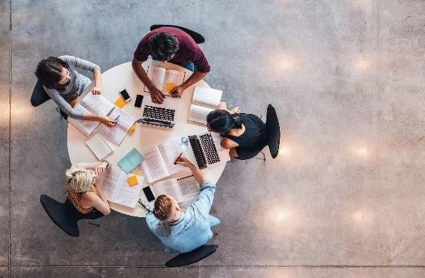 An aerial shot of a group of five temporary workers studying while they're at the office.