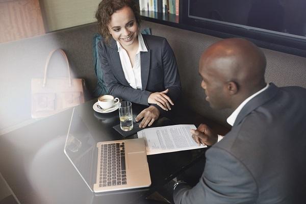 A woman and a man at a table in a coffee house, having a meeting. One of them is a recruitment consultant.
