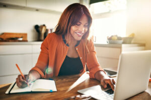 Woman sitting at the table working on her laptop smiling