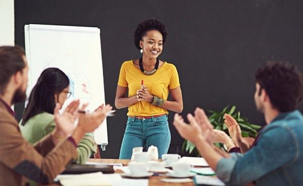 Woman giving a presentation is applauded by her colleagues