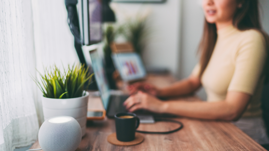 A photo of a lady typing at her laptop alongside a mug of tea