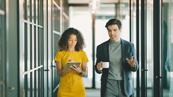 Man and woman walking together in office in discussion