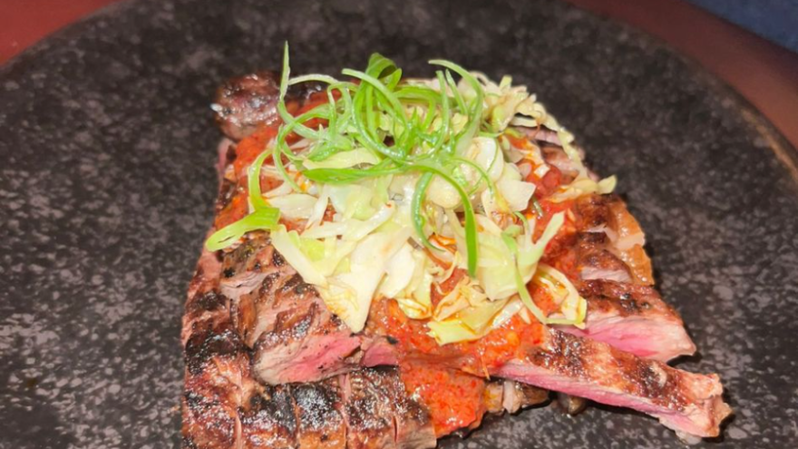 A photo of a meat dish with a salad serving placed on top.