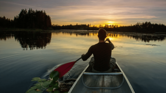 A man rowing on a lake at sunset