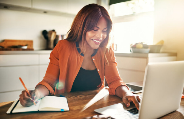 Smiling young female entrepreneur working at her kitchen table
